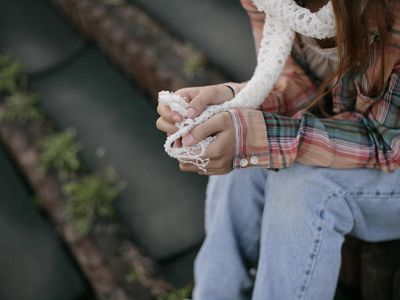 close-up of young woman's hands holding white scarf