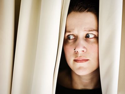 woman with agoraphobia peeking out from curtains