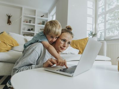 Boy doing mischief on laptop while standing behind mother at home