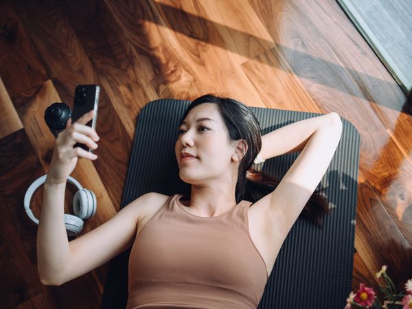High angle shot of young woman checking her smartphone during a workout.