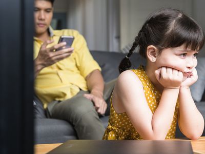 Sad Girl Sitting With Father Looking at Cell Phone