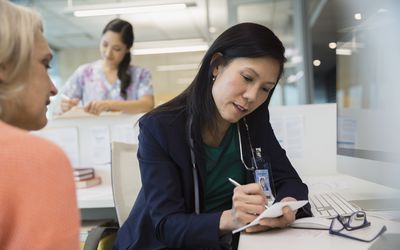 Doctor writing prescription for patient in clinic office