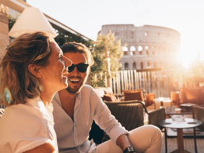 Romantic couple smiling at sunset in Rome, Italy. Colosseum in background