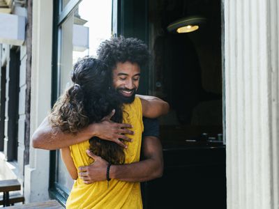 Two friends greeting each other and embracing outside a restaurant