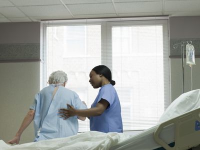 Woman in hospital being helped by nurse.