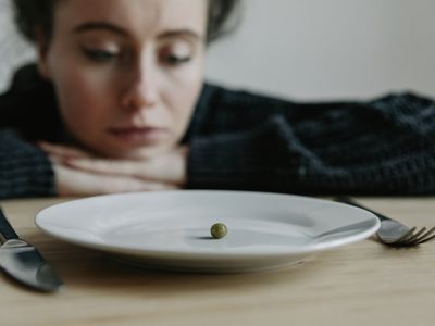 Woman staring at a plate with one pea on it