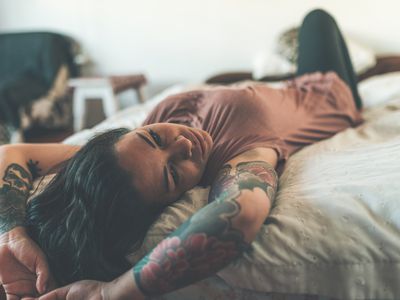tattooed person laying on bed relaxing
