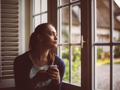 Detached woman looking out the window with no emotion.