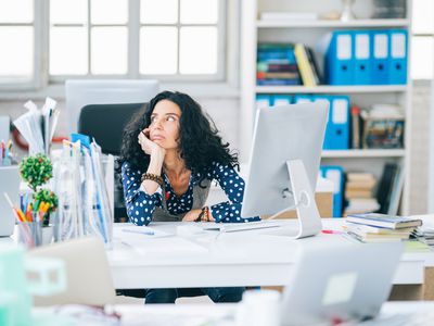 Woman sitting at her desk distracted.