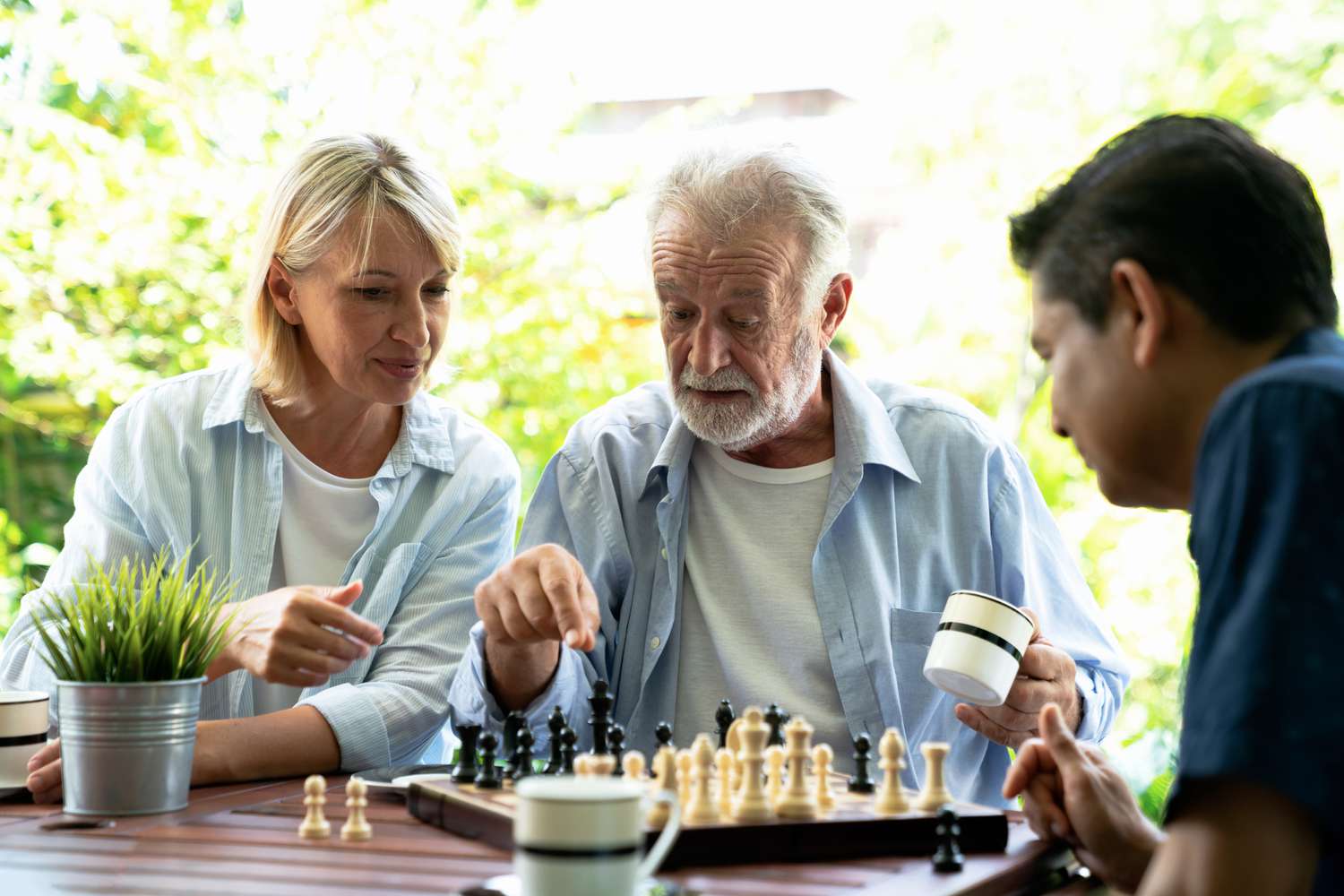 Woman and man playing chess with an older man