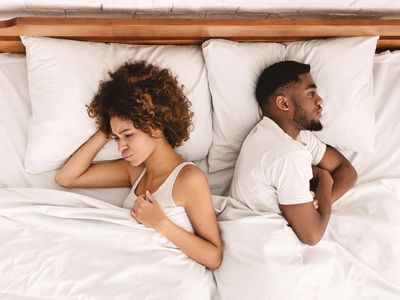 African-american couple ignoring each other in bed