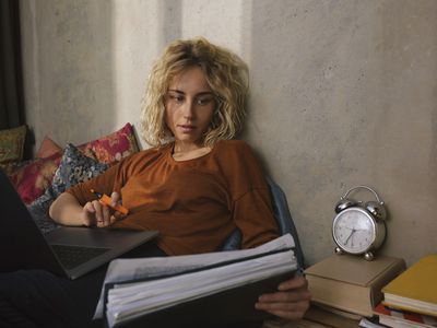 Portrait of blond student on bed working on laptop