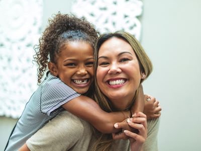 Asian Mother with daughter of mixed Chinese and African American ethnicity at home indoors posing playfully for portraits smiling and being silly