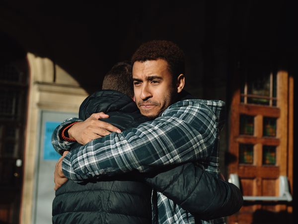 Two men hug outside of a building