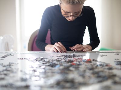 Young woman with glasses working on a puzzle.