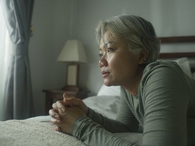 older person depressed while thinking on their bed