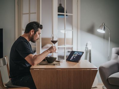 Man having a glass of wine and talking to a friend online.