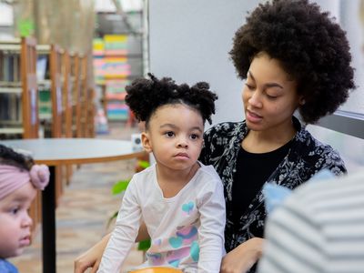 Mother and toddler daughter speak with others during a therapy support group meeting