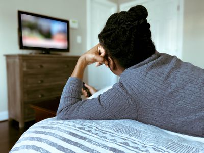 Rear view of mid adult black woman watching tv in bed