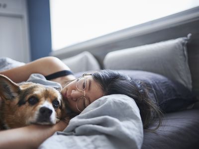 Mid adult woman lying in bed with dog