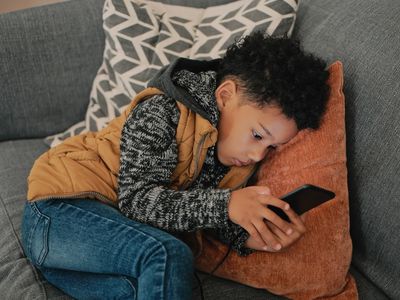 child sitting on the couch texting on the phone