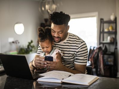 Father working from home while holding toddler