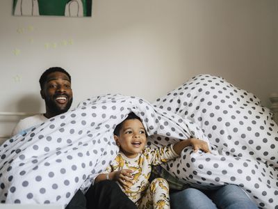 Smiling family with spotted blanket enjoying in bedroom