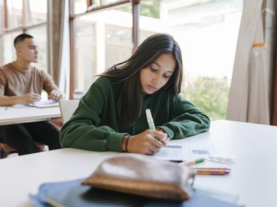 A high school student sitting at her desk concentrating during a test in class.