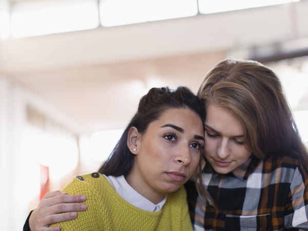 Young woman consoling, hugging sad friend