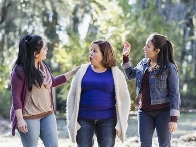 Senior Hispanic woman with adults daughters walk in park