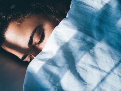 Lady sleeps in bed tossing turning in dream under blanket 