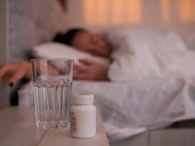 Woman sleeping with bottle of sleeping pills in the foreground.
