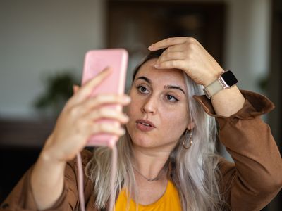 Blonde woman mirroring herself using mobile screen at home