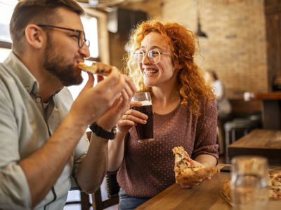 Romantic couple eating pizza and drinking beer in a pub