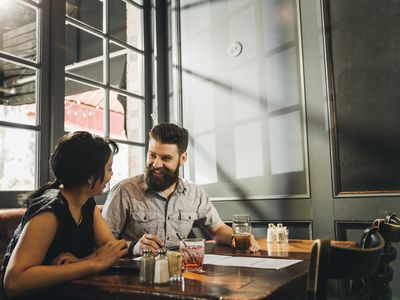 Man talking with female friend while having drink in bar - stock photo