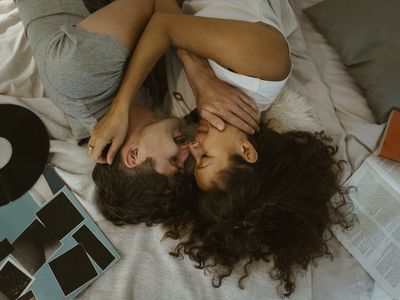 Directly above view of romantic couple rubbing noses while lying on bed at home