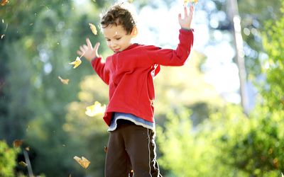 Child tossing autumn leaves into the air