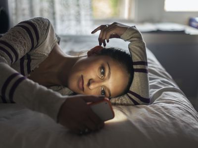 Teen (16-17) girl lying on bed using smartphone