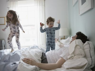 dad with kids jumping on bed