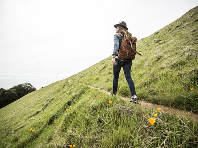 person walking a trail on the side of a mountain with grass