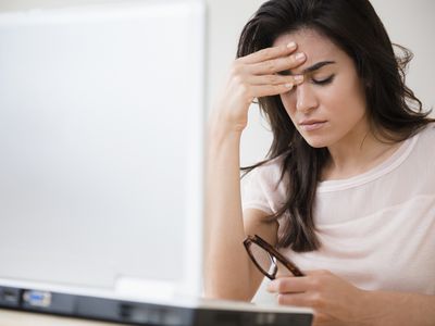 Stressed woman rubbing her forehead at laptop