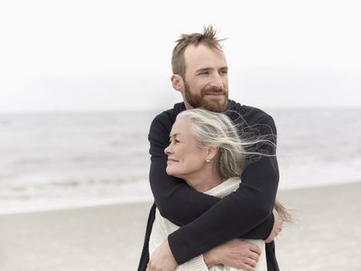 Adult son hugging senior mother on the beach