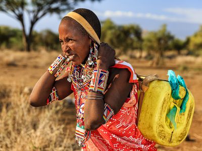 African woman from Maasai tribe carrying water to their village