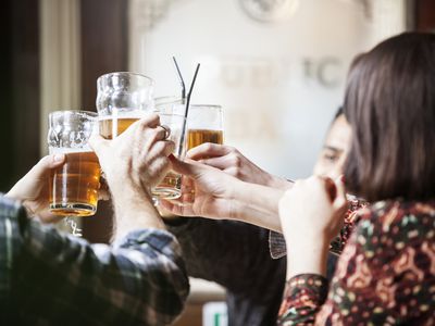 A group of friends toasting with beer mugs at a pub