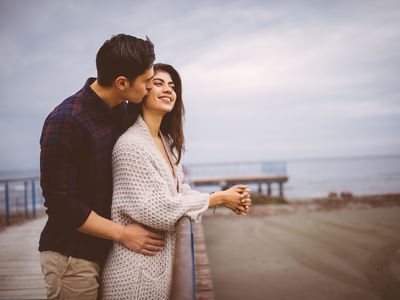 Young man hugging his girlfriend on a pier