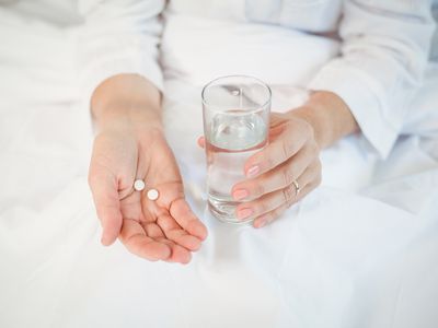 woman in bed taking medication with water
