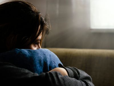 person depressed hugging their pillow on a couch