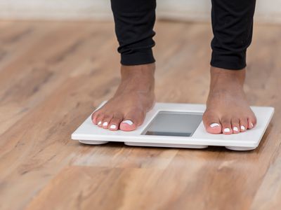 An unrecognizable woman stands on a bathroom scale