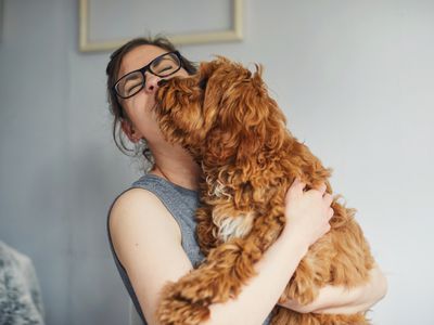 Woman getting a kiss off her pet puppy dog