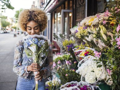 Smiling woman smelling hydrangeas outside flower shop